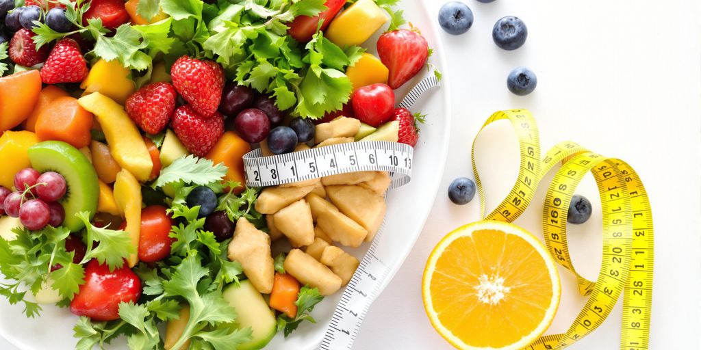 Plate of fruits and vegetables with a measuring tape.